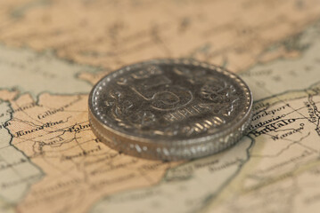 Five rupee steel coin on top of a map. Concept of traveling cheap.