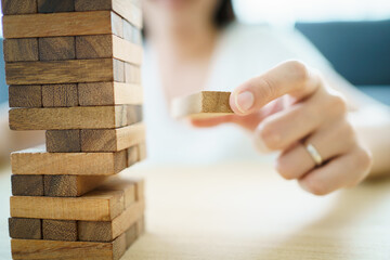 Happy Asian woman enjoy playing a wood block game called wood block tower in the living room during the free time.