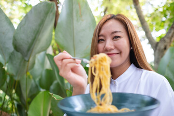 Portrait image of a young woman eating spaghetti in the outdoors restaurant