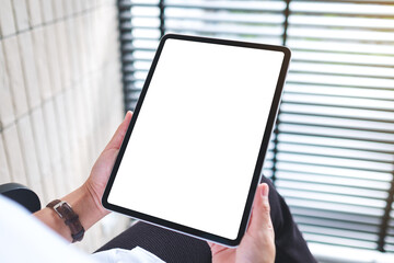 Mockup image of a woman holding digital tablet with blank white desktop screen in office