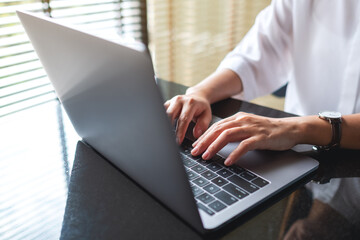 Closeup image of a woman working and typing on laptop computer keyboard in office