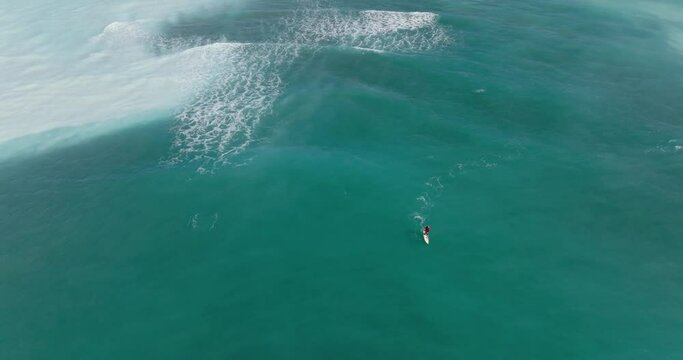 Aerial view of Surfer. Ocean waves seen from above. Person surfing on surf board. Top down view of seascape