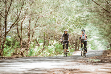 Obraz premium Two young Muslim women enjoying cycling together on the street