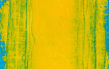 abstract bright colored background: a smeared flat wide spot of yellow paint on a blue fabric close...
