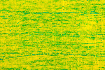 abstract bright colored background: yellow paint on a blue fabric close up, translucent green colo