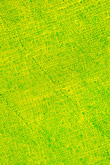 abstract bright colored background: yellow paint on a blue fabric close up, translucent green colo
