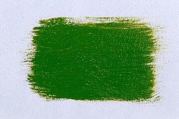 wide brush stroke with saturated bright light olive-green paint on a white background, close up