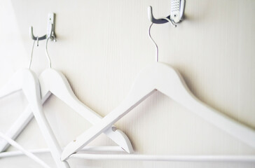 Empty clothes hanger hook, close up. Some wooden white hangers on white wooden background, selective focus.