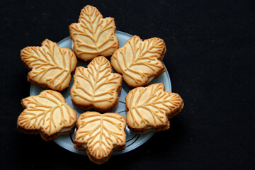 Delicious cookies filled with vanilla cream made with honey or maple syrup from Canadian trees, the traditional sweet of Canada in white plate on a black bakground
