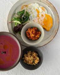 High angle view of food on the white background.  Fried egg, green salad, keema curry, cous-cous and beet soup.