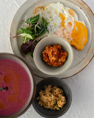 High angle view of food on the white background.  Fried egg, green salad, keema curry, cous-cous and beet soup.