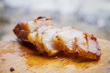 Smoked lard is cut into pieces and lies on a wooden board. Delicious fatty food on a camping trip in nature. National dishes.