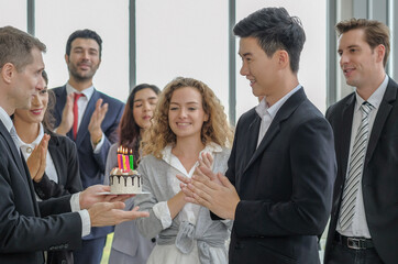 Multi ethnic diversity business people surprise birthday to asian male colleague with happy smiling faces, selective focus.
