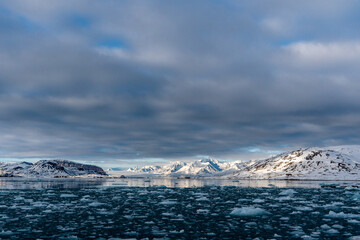 Naklejka premium Sea with melting ice cubes, snowy mountains In Svalbard, Norway. Global Warming.