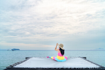 A single woman in a colorfull dress sits by the sea on a summer morning, relaxed and freedom on vacation and leave space for text input.