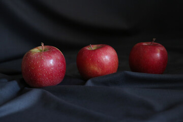 red apples on dark draped fabric, blurred 