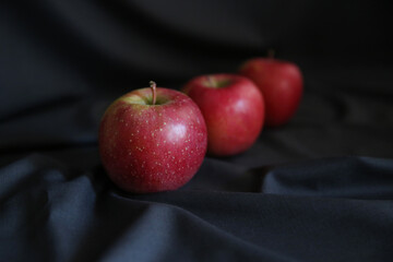 red apples on dark draped fabric, blurred 