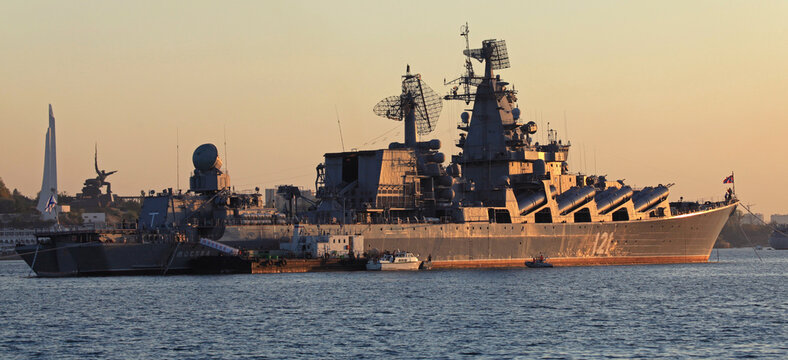 Military cruiser "Moscow" in Sevastopol bay. Russian (Soviet) guards missile cruiser, the main ship and flagship of Black Sea Fleet. Sunset colors view. Panorama