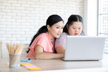 down syndrome teenage girl and her teacher using laptop computer together on a table