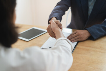 close up view hands of agent and client shaking hands after signed contract buy new apartment.