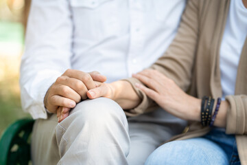 Two mature people holding hand while sitting relax in the park.