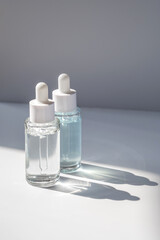 Two laconic bottles of cosmetic liquid in the rays of the harsh sun.