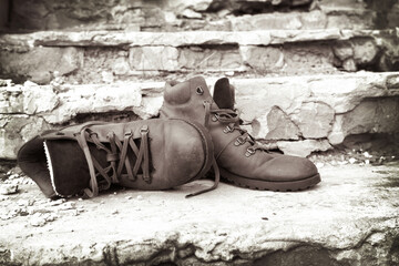 A pair of old worn brown leather shoes with laces on an old brick porch.The concept of proper care...