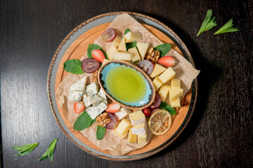 Cheese assorted with honey, decorated with fresh fruits, strawberries, grapes, lemon, walnuts