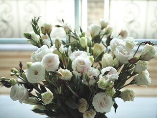 Beautiful spring delicate bouquet of white flowers of lisianthus, eustoma on the window close-up. Mother's day card. Wedding concept. Floristry, floral studio