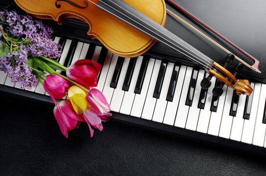 Electric guitar, synthesizer keyboard, maracas and a bouquet of tulips and lilies of the valley on a red table.