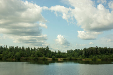 Fototapeta premium Summer landscape with a beautiful lake with fir trees against a cloudy sky