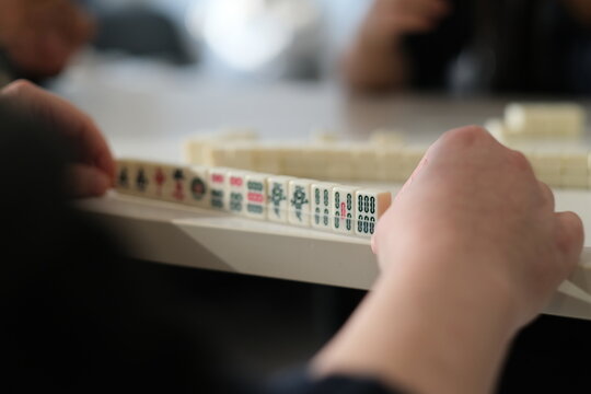 over the shoulder view of people playing Chinese mahjong game.