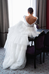 Back view of bride in wedding dress in luxury hotel room