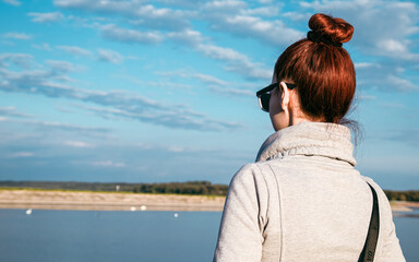 Fototapeta na wymiar A young woman looking the beauty of the river and nature. Back view. An optimistic look and a relaxing day. 