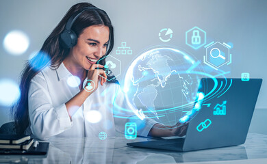 Smiling woman with laptop on desk, earth sphere hologram with digital icons