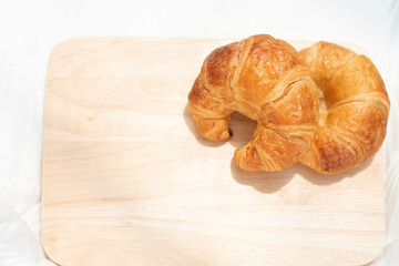 Croissant isolated on wooden plate, fresh baked bread for easy breakfast.