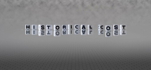 historical cost word or concept represented by black and white letter cubes on a grey horizon background stretching to infinity