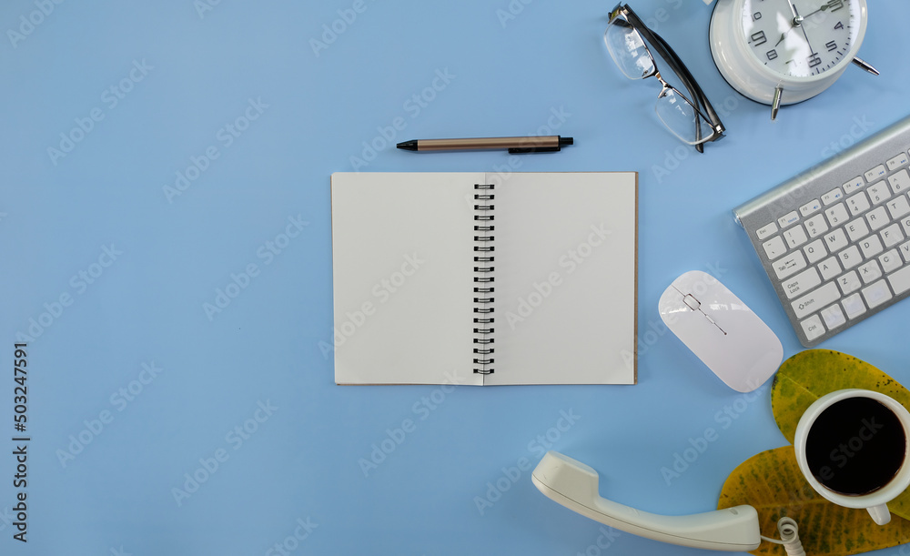 Canvas Prints Blank notepad with a pen rests on an office desk table, surrounded by computer equipment and various papers. flat lay, top view, money and banking background