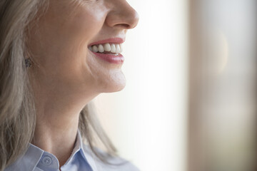 Happy mature woman toothy smile side view. Positive senior lady showing row of healthy white teeth,...