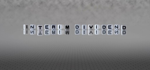 interim dividend word or concept represented by black and white letter cubes on a grey horizon...