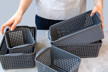 The girl uses plastic gray baskets to store things. Organization of home space, house order.
