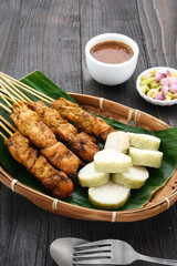 Chicken satay (sate ayam) with Lontong and peanut sauce. One of the popular street food in Indonesia. Selective focus.
