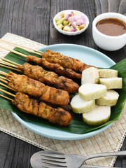 Chicken satay (sate ayam) with Lontong and peanut sauce. One of the popular street food in Indonesia. Selective focus.

