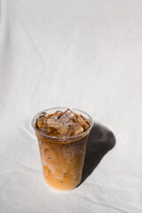 Close-up plastic glass of iced coffee with milk on the table