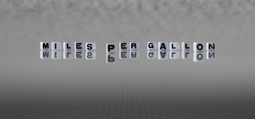 miles per gallon word or concept represented by black and white letter cubes on a grey horizon...