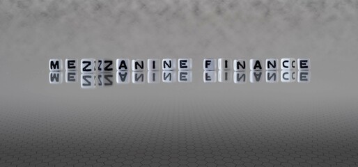 mezzanine finance word or concept represented by black and white letter cubes on a grey horizon...