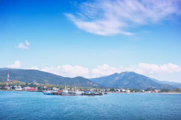 Fototapeta na wymiar Ferry landing pier with fishing ship. Landscape with island Samui, blue sea and sky.