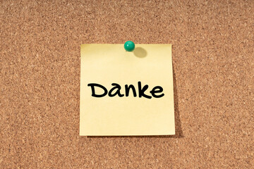 Thanks word in german language on yellow note on cork board