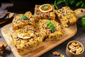 Pumpkin blondie bars with chocolate and walnuts close-up. Brownie pie slices on a serving wooden...