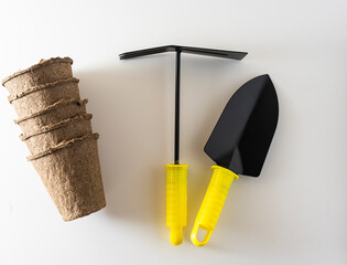garden tools shovel and rake and peat cups on a white background